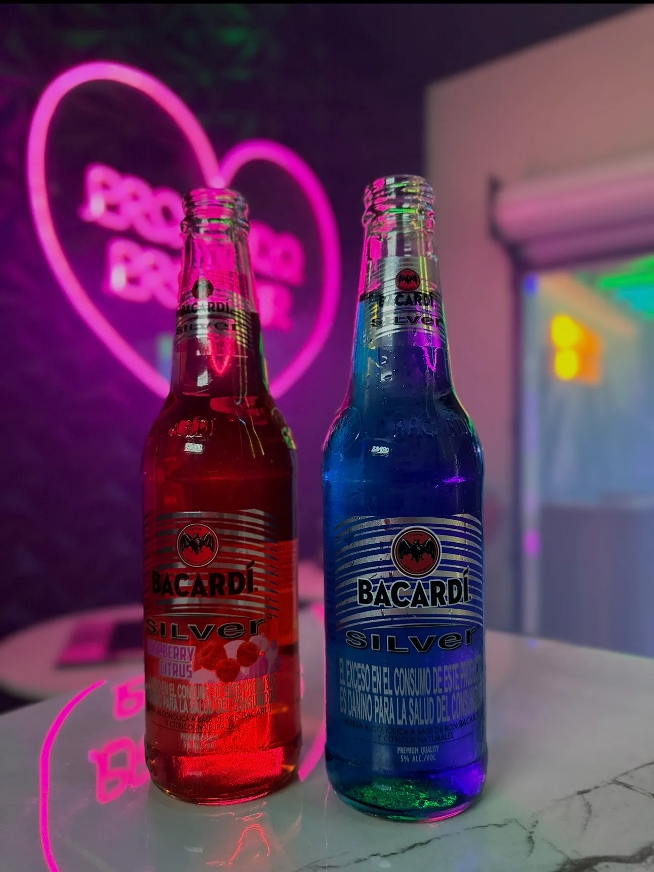 Red and blue Bacardi Silver bottles with neon