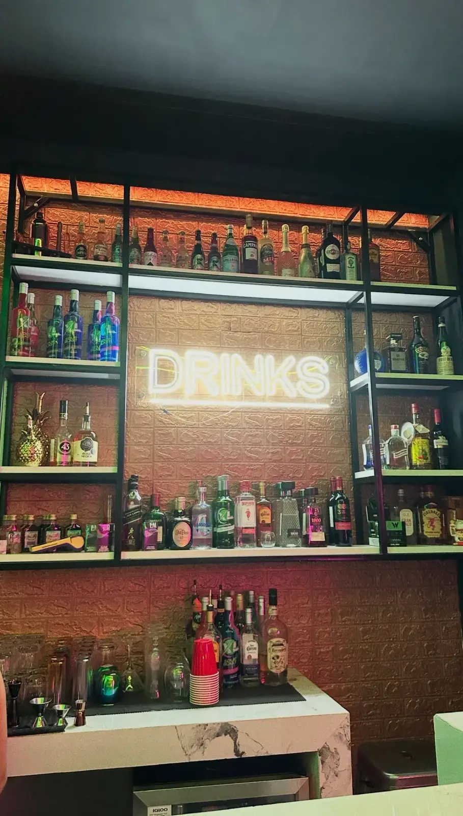 Premium liquor shelf with neon DRINKS sign