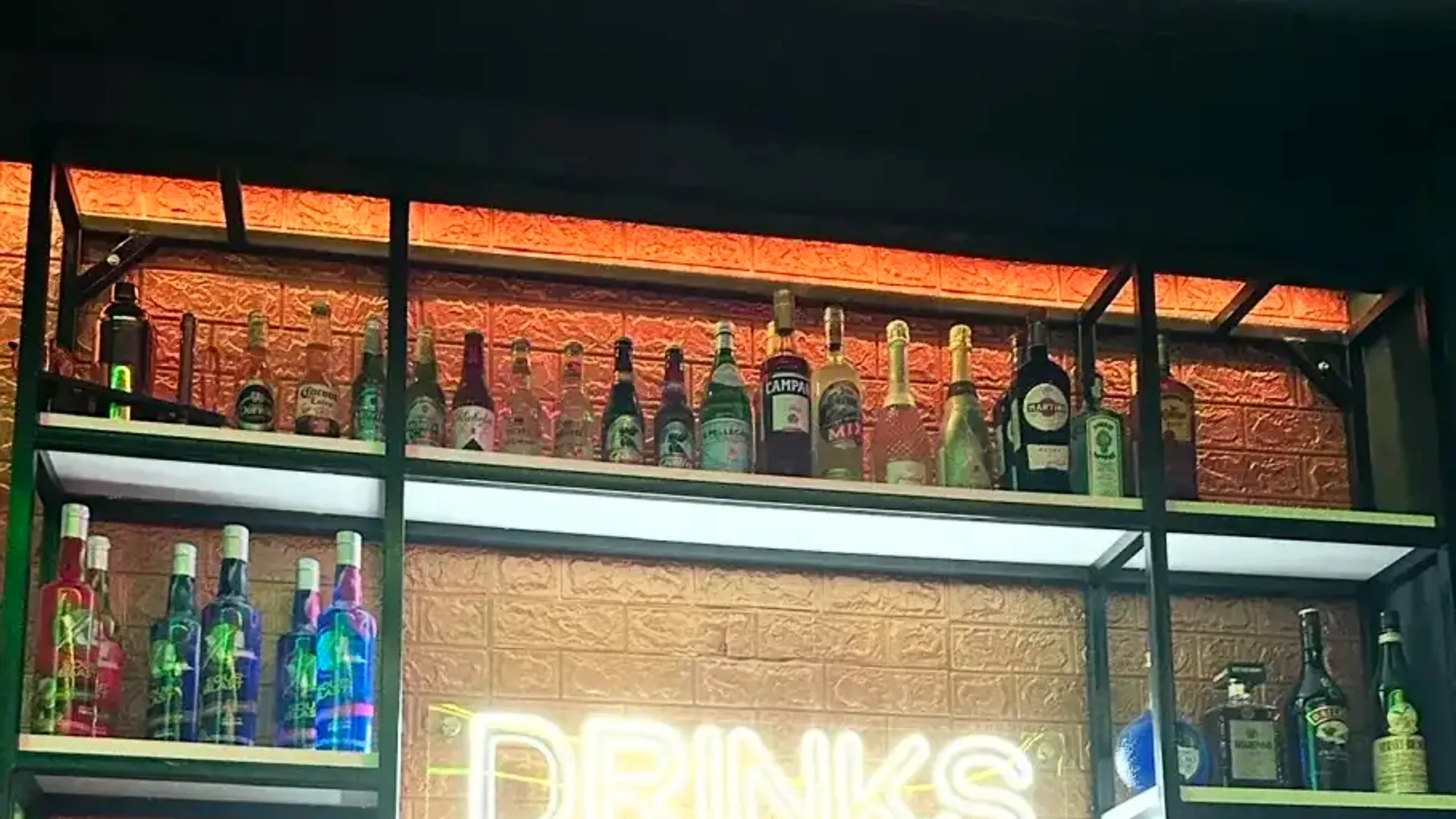 Premium liquor shelf with DRINKS neon at Single's Bar